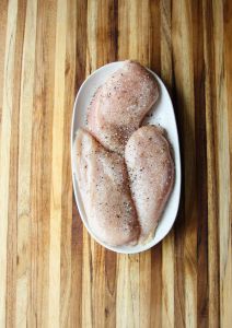 Raw chicken seasoned with salt and pepper.