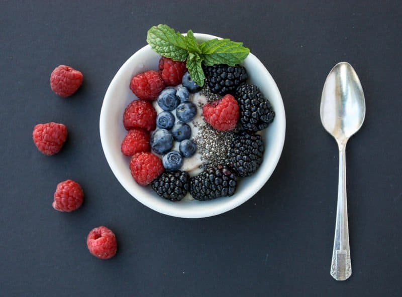 A bowl of fruit on a plate, with Berries