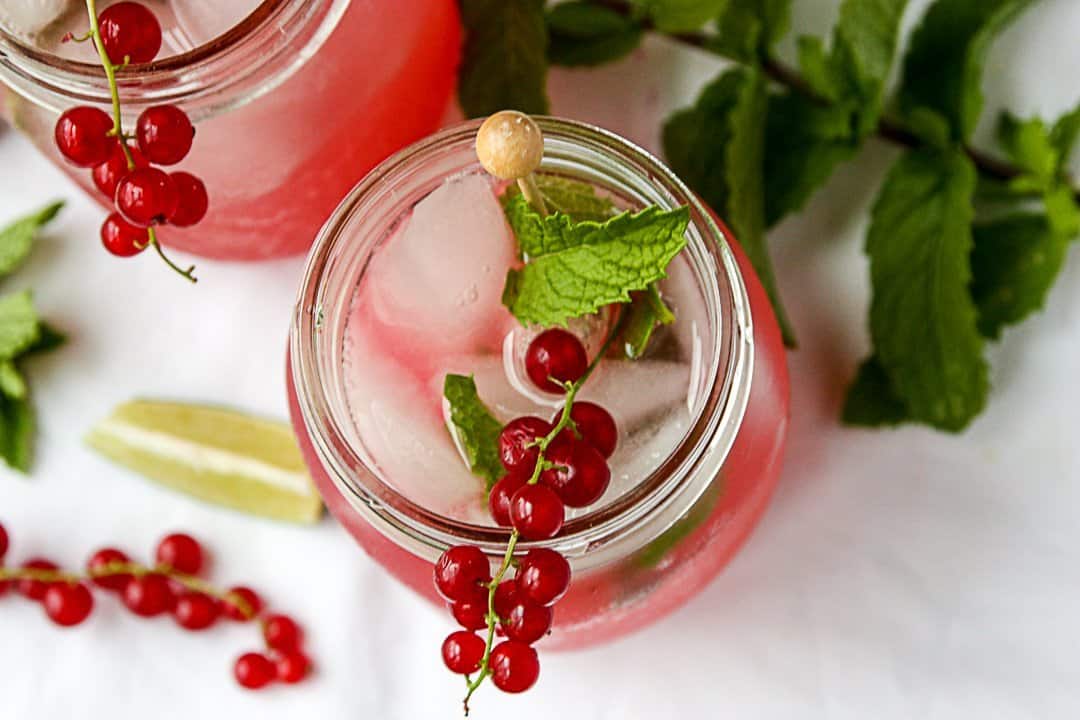 A drink garnished with red berries and a mint leaf