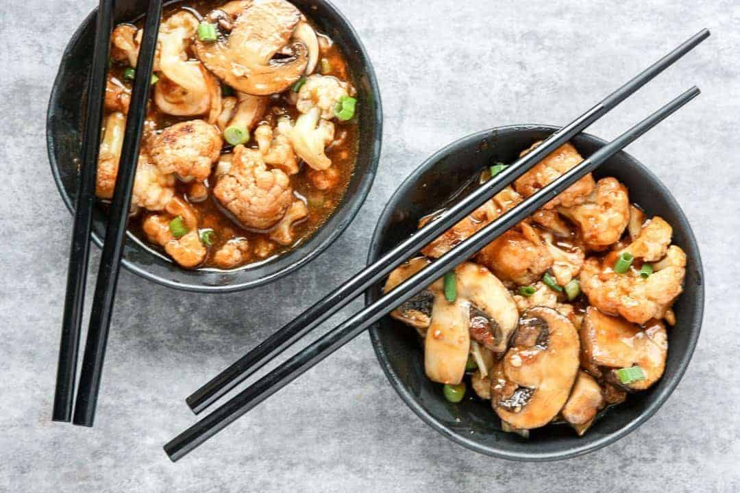 Two black bowls of food with chopsticks