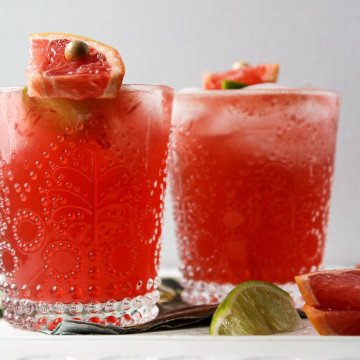 Two glasses filled with pink liquid and ice