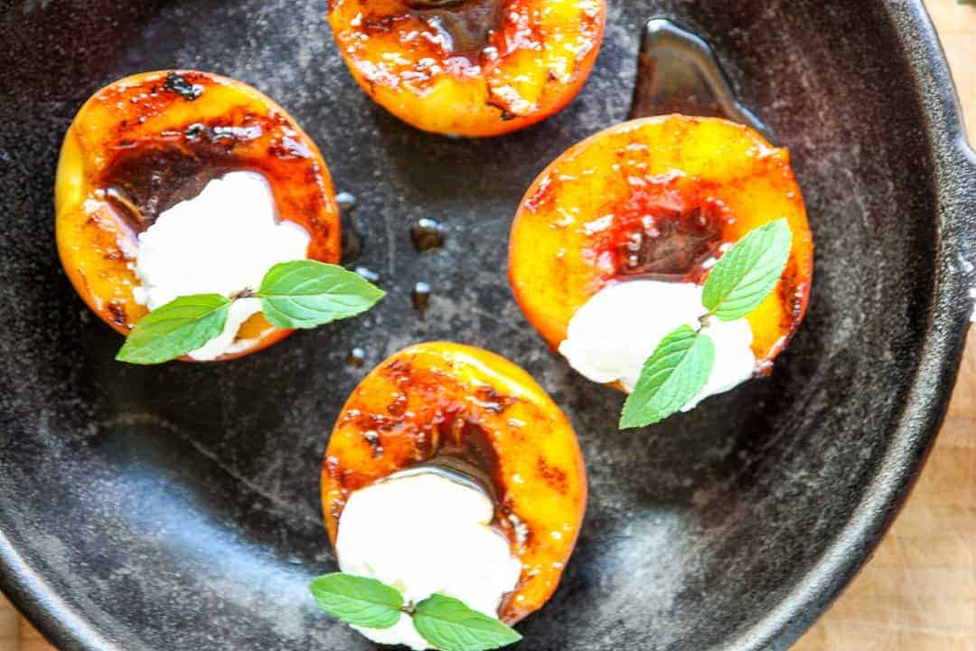 A plate of peach halves topped with whipped cream