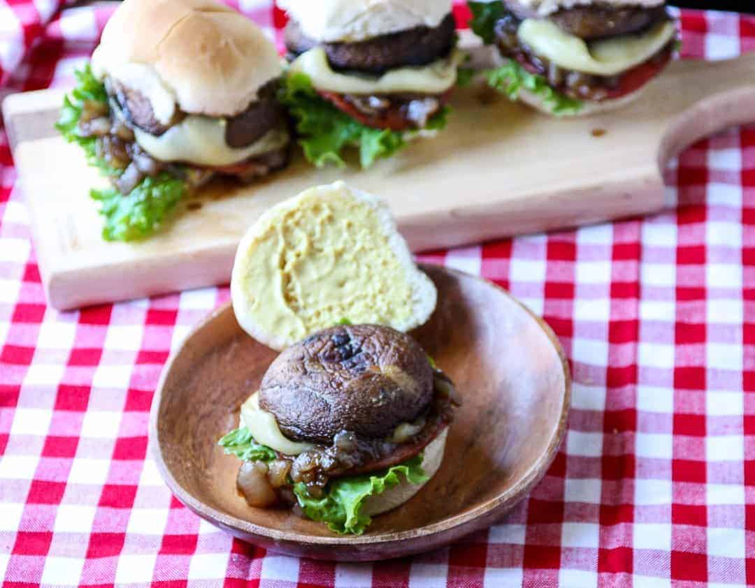 A plate of sliders on a table with mushrooms and cheese