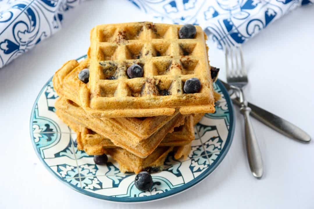 A stack of waffles on a plate, with blueberries