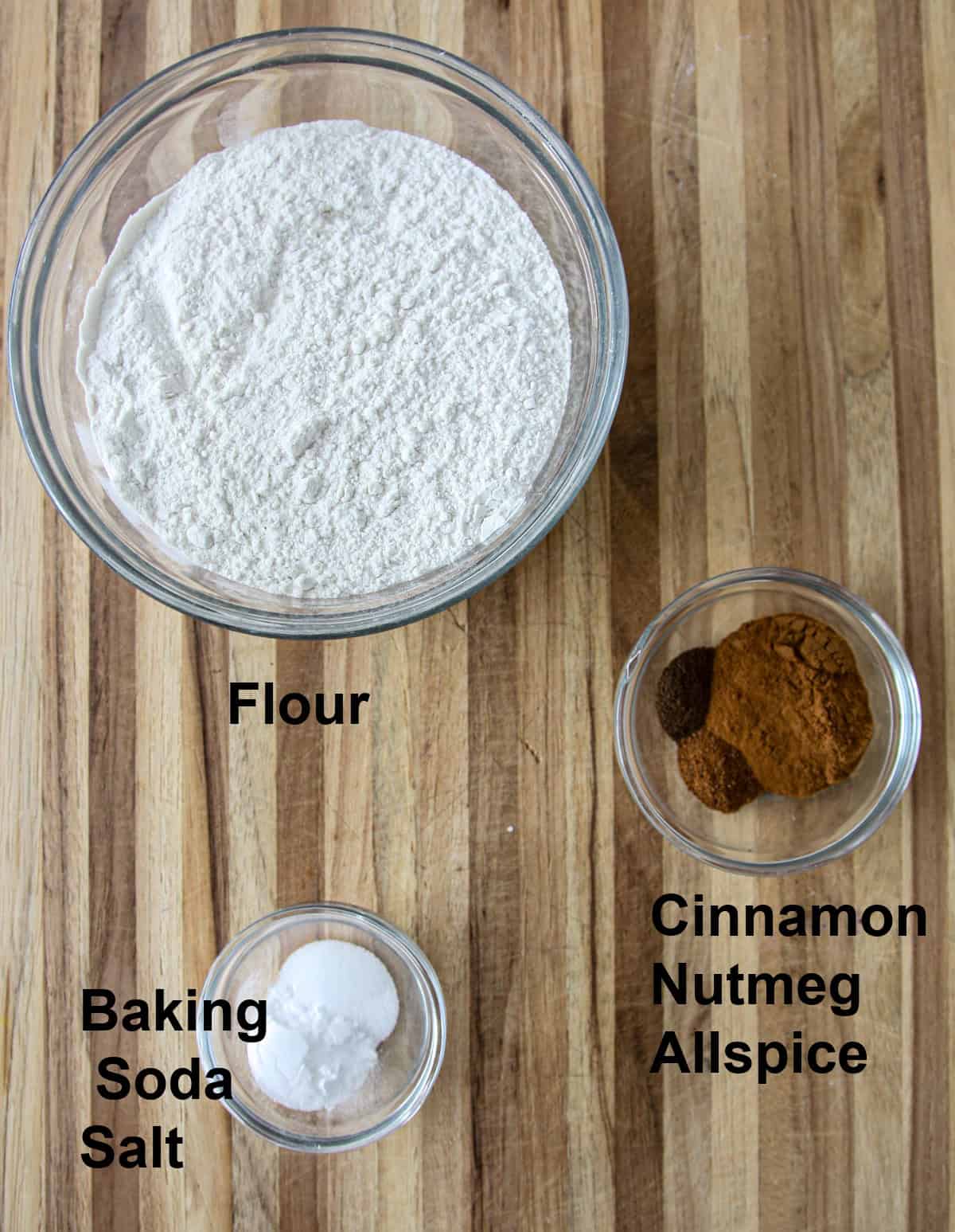 The dry ingredients in glass bowls on a wooden board.