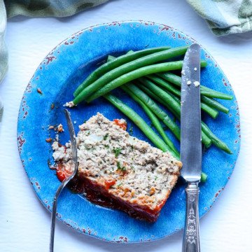 A piece of meatloaf on a plate with a fork and knife