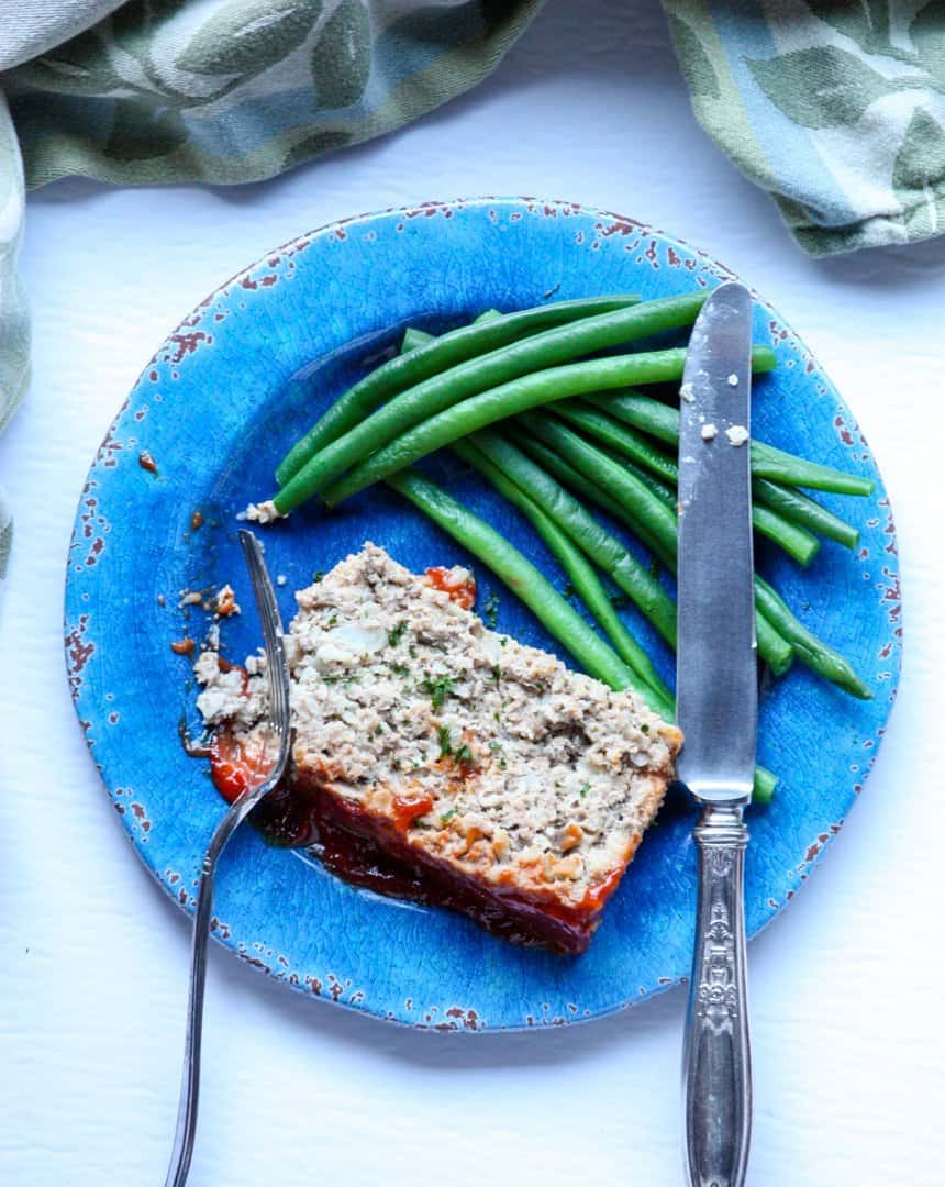 A piece of meatloaf on a plate with a fork and knife