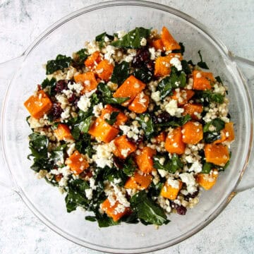 Butternut squash salad with feta, buckwheat and kale, in a glass bowl.