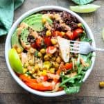 A bowl of food with avocado and chicken