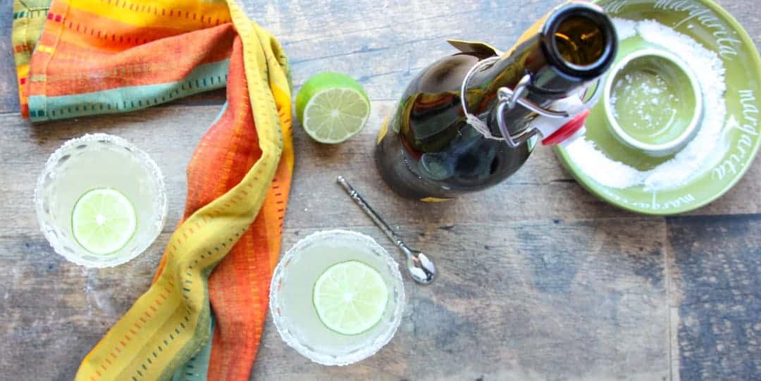 A cocktail on a table with a bottle