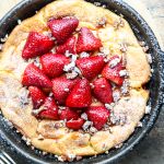 Top shot of strawberry Dutch baby gluten free in cast iron skillet.