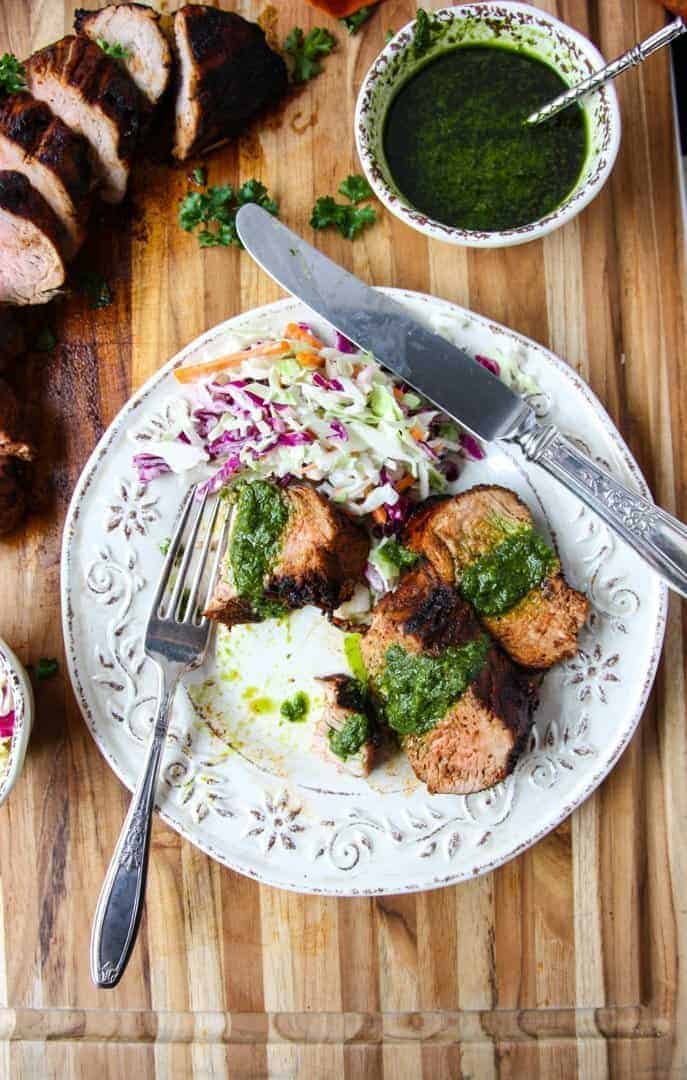 A plate of food on a wooden table, with Pork tenderloin