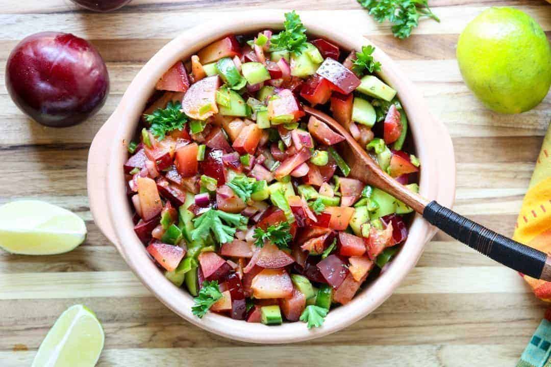 A bowl of fruit salsa with a wooden spoon
