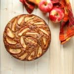 An apple sitting on top of a wooden cutting board, with Cake