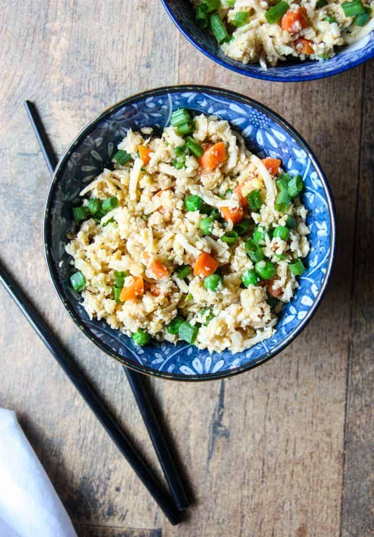 Cauliflower rice in a blue and white bowl with black chopsticks