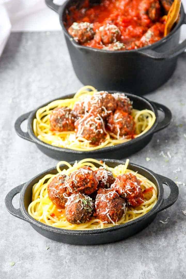 Top shot of two small black skillets with spaghetti and meatless meatballs
