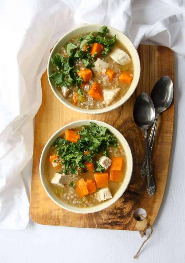 Two bowls of soup on a cutting board, with two spoons