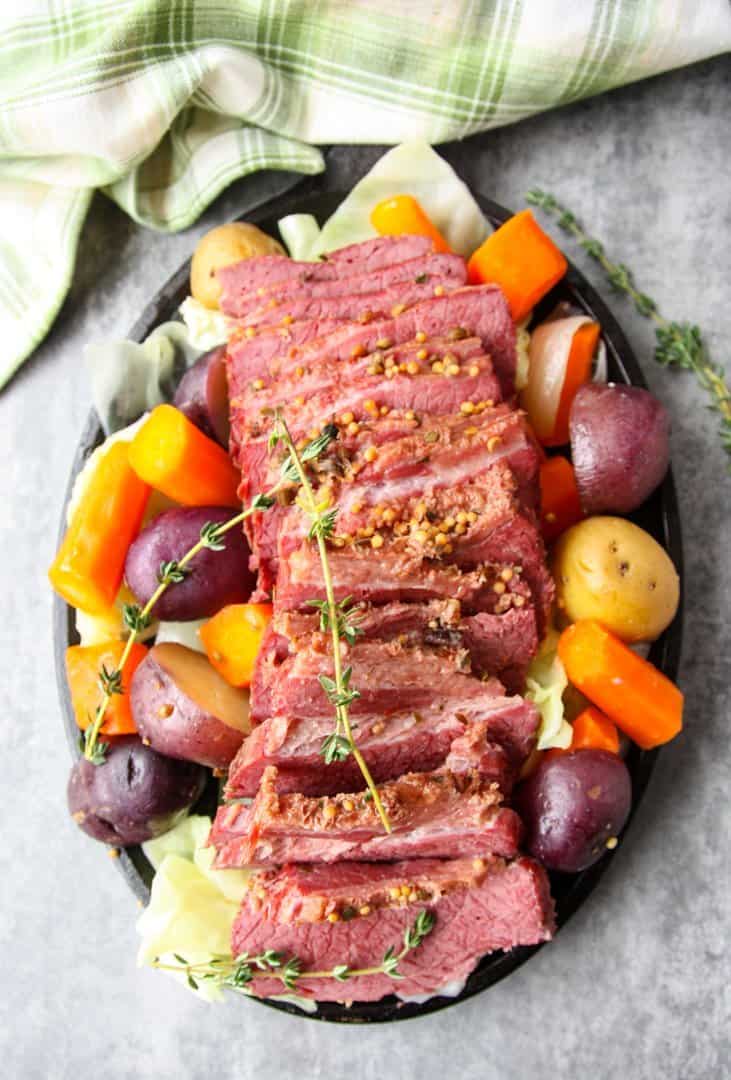 A round black plate of vegetables and sliced meat,