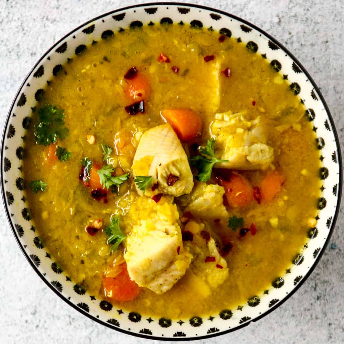 Turkey lentil soup in a black and white bowl.