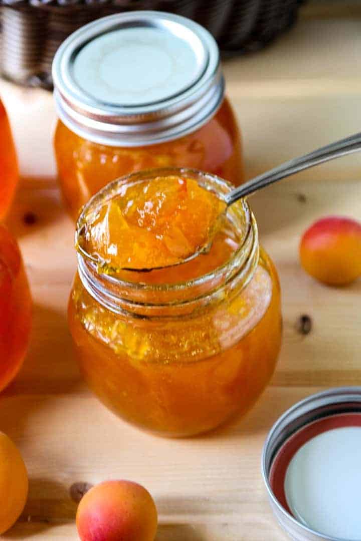 A close up of an open jar of jam with a spoon in it