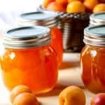 Four jars of apricot jam and a basket of fresh apricots