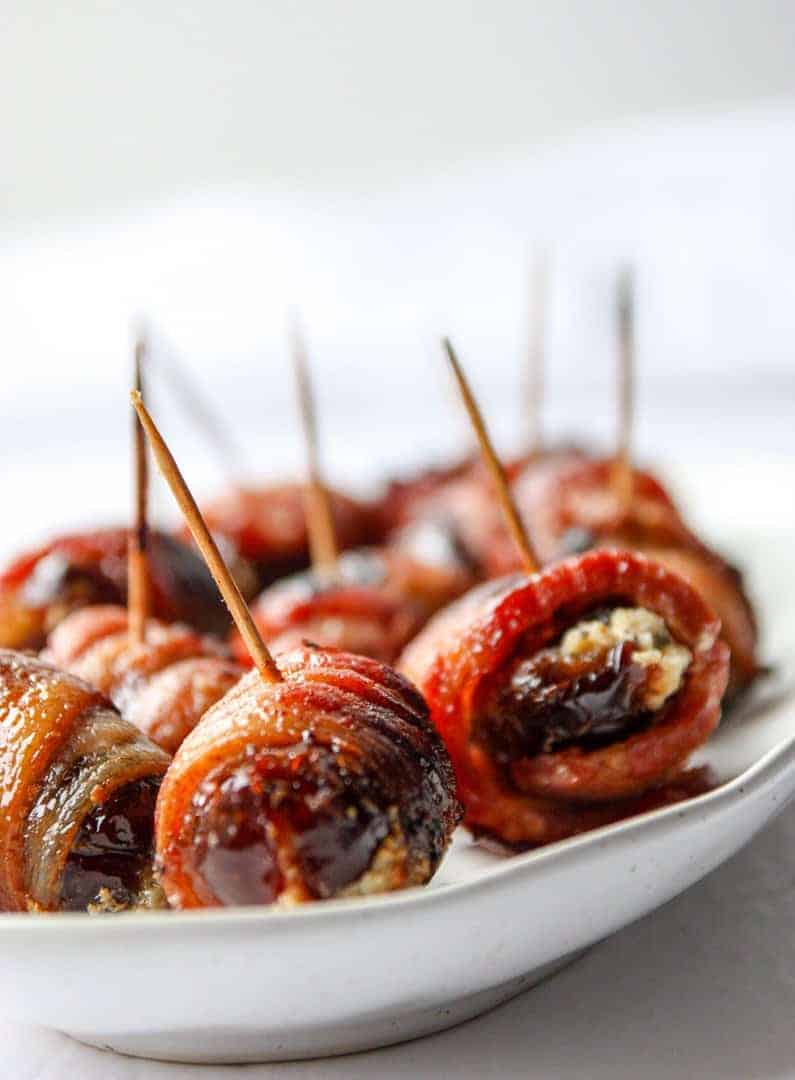 dates wrapped in bacon with toothpicks on a plate