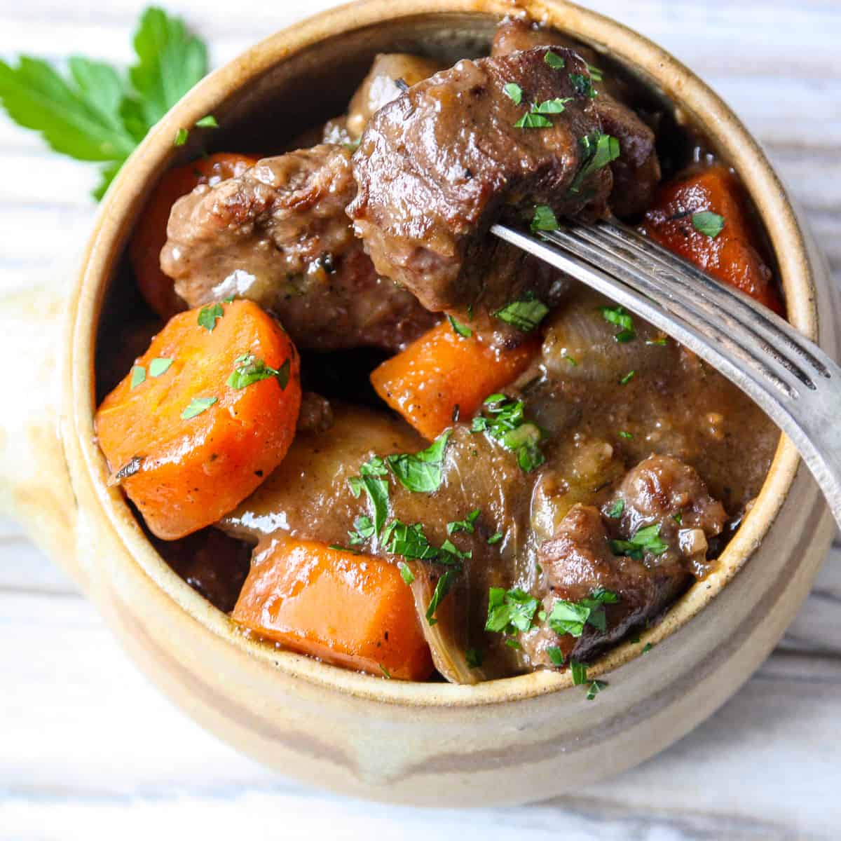 A bowl of Irish beef stew with a fork inserted.