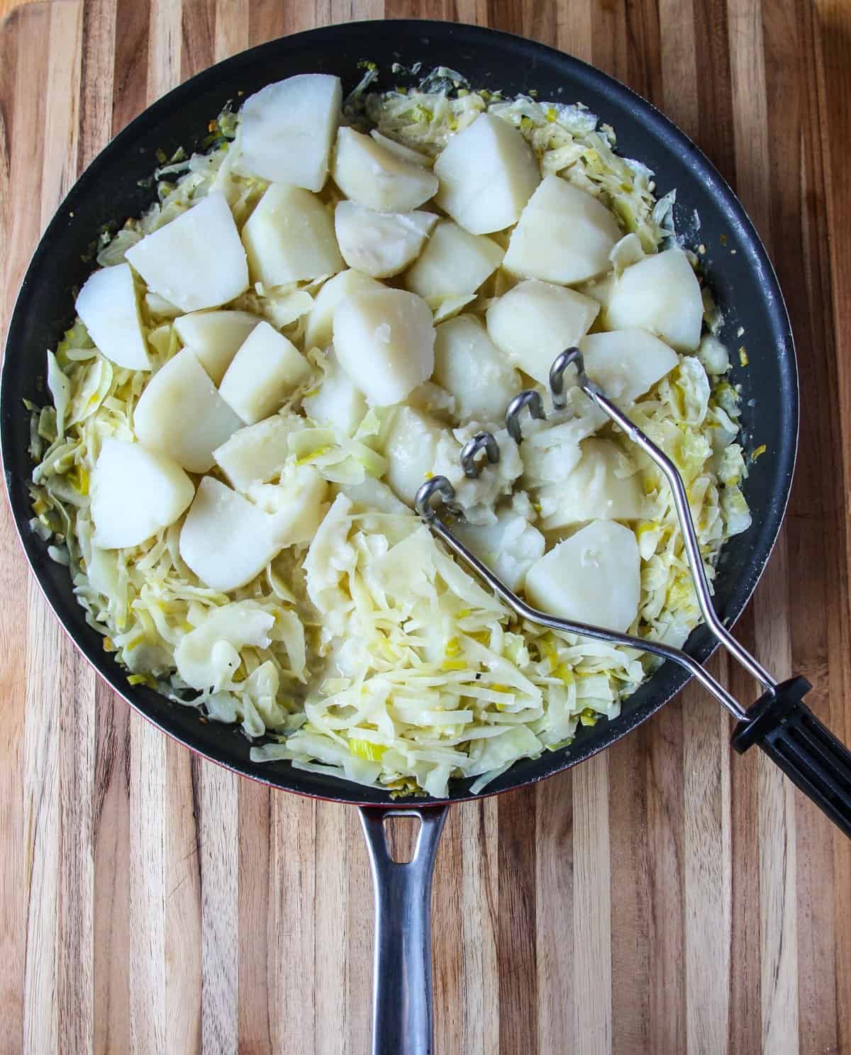 Cooked potatoes added to a pan of sautéed cabbage.