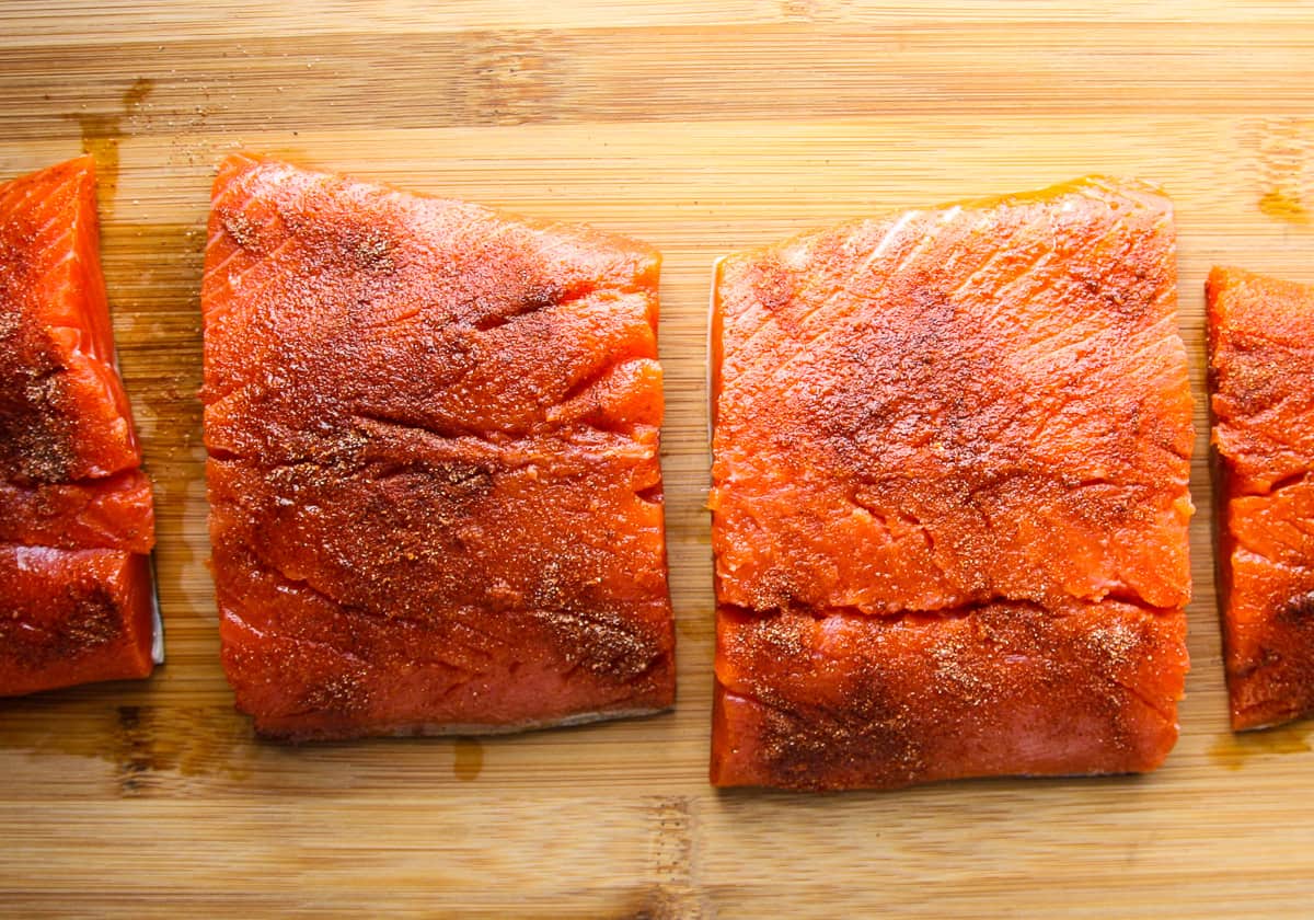 Salmon fillets being seasoned before cooking in the air fryer.