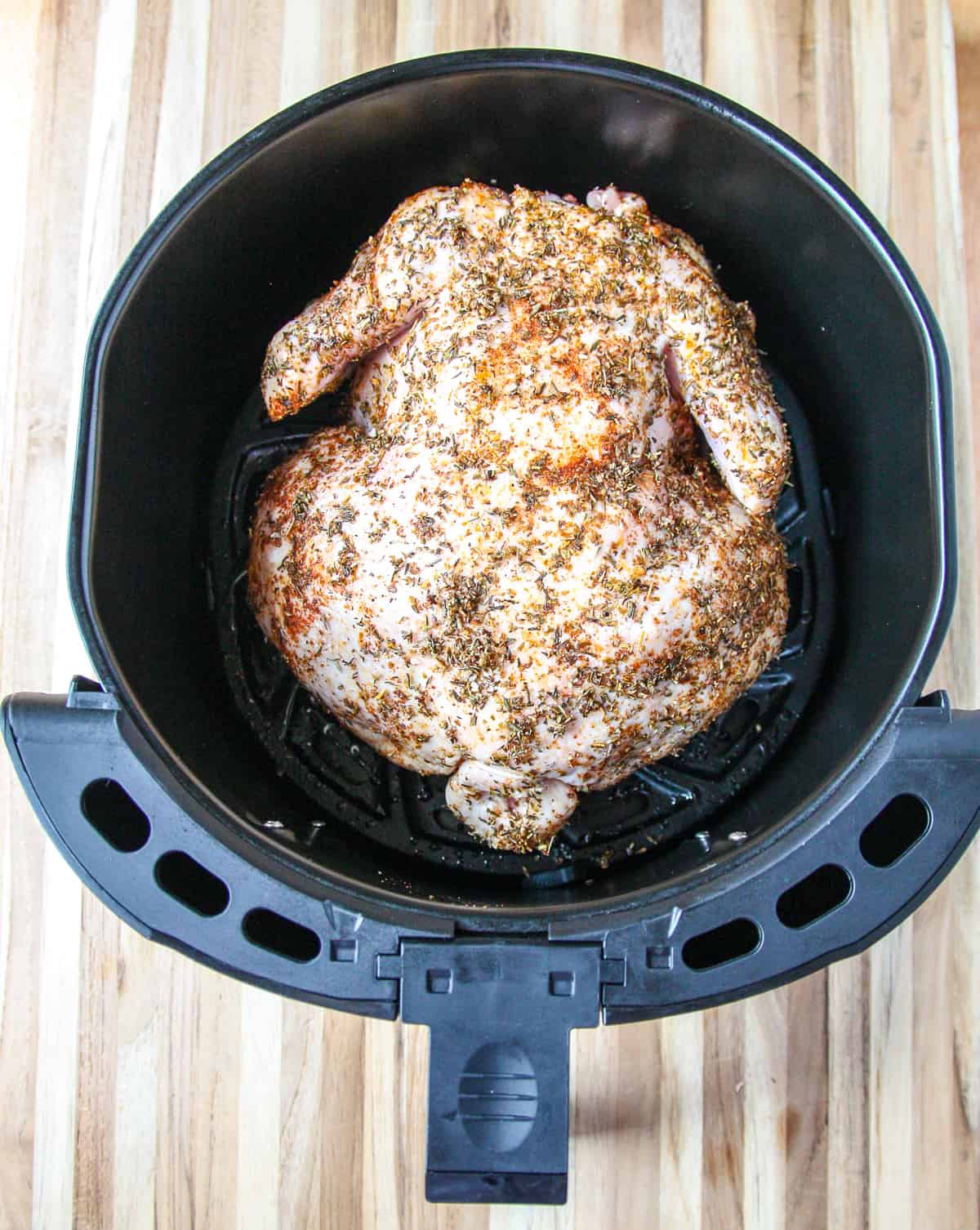 The chicken is placed breast side down in the air fryer basket.