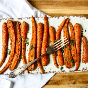 Air fried carrots on a white platter with a fork.