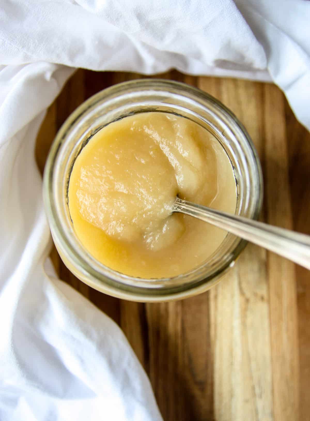 A jar of homemade applesauce with a silver spoon.