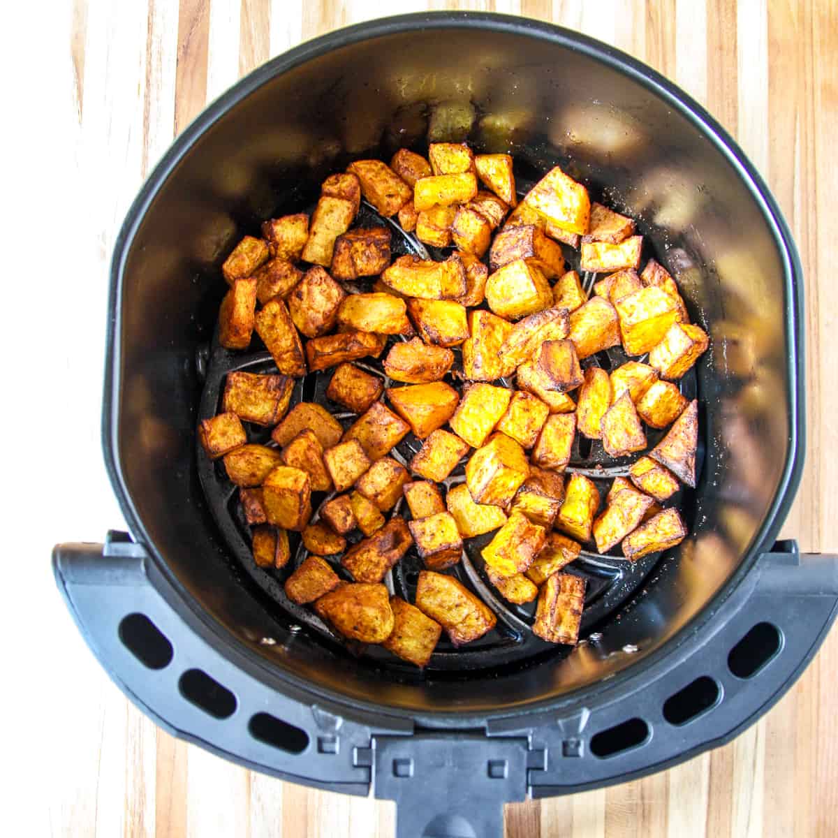 Cooked squash cubes in the air fryer basket.
