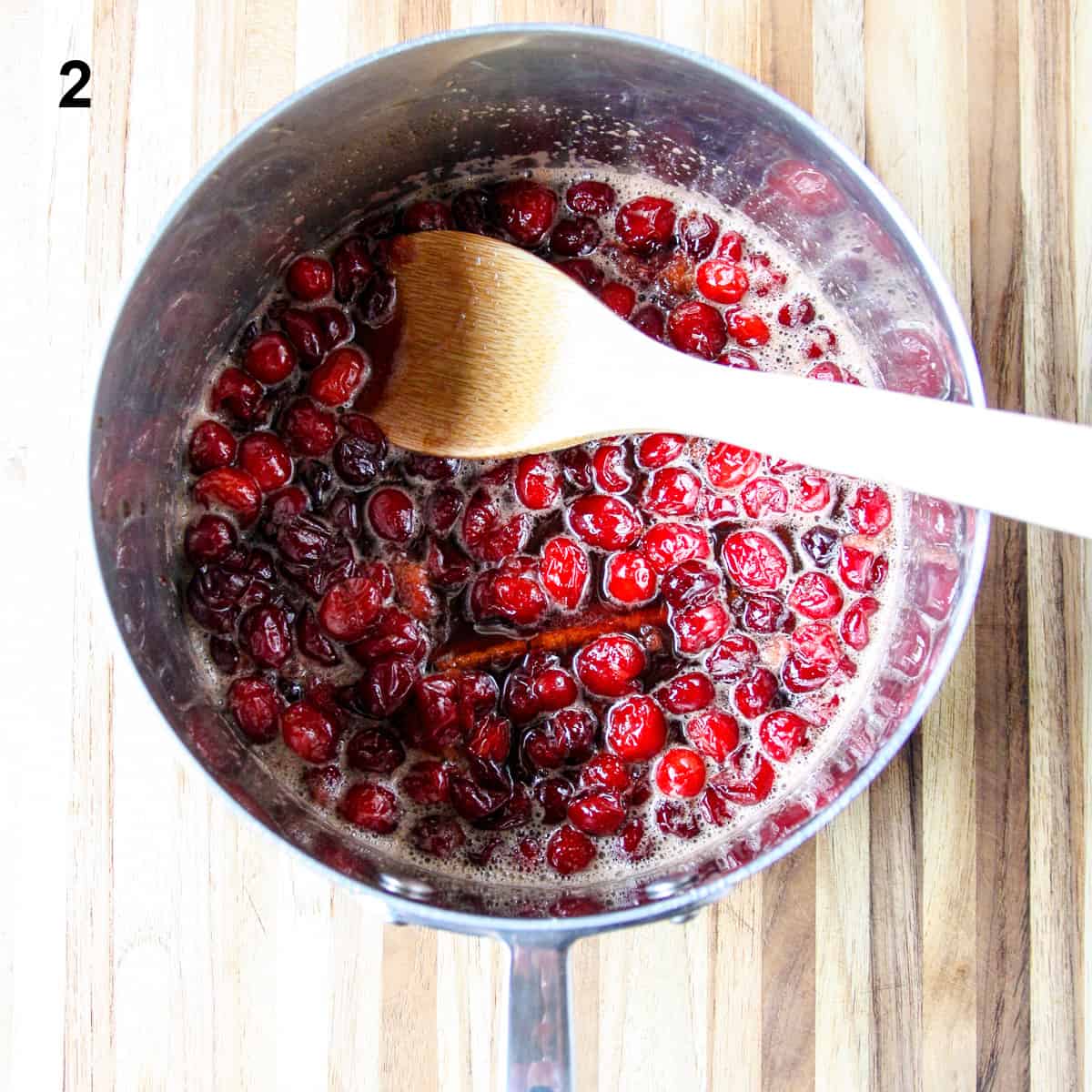 The simmering sauce being stirred with a wooden spoon.