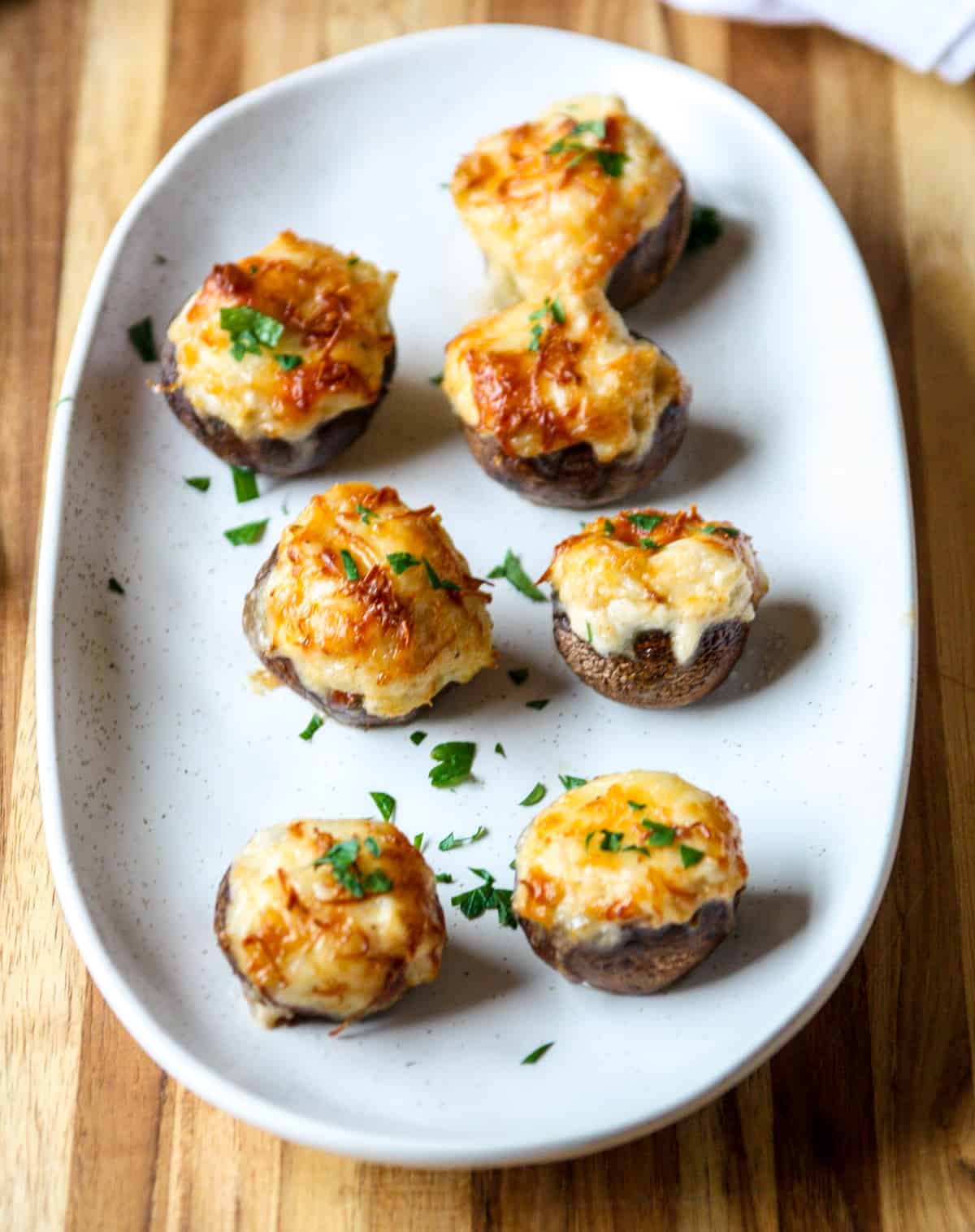 Air fryer stuffed mushrooms on a white serving dish.