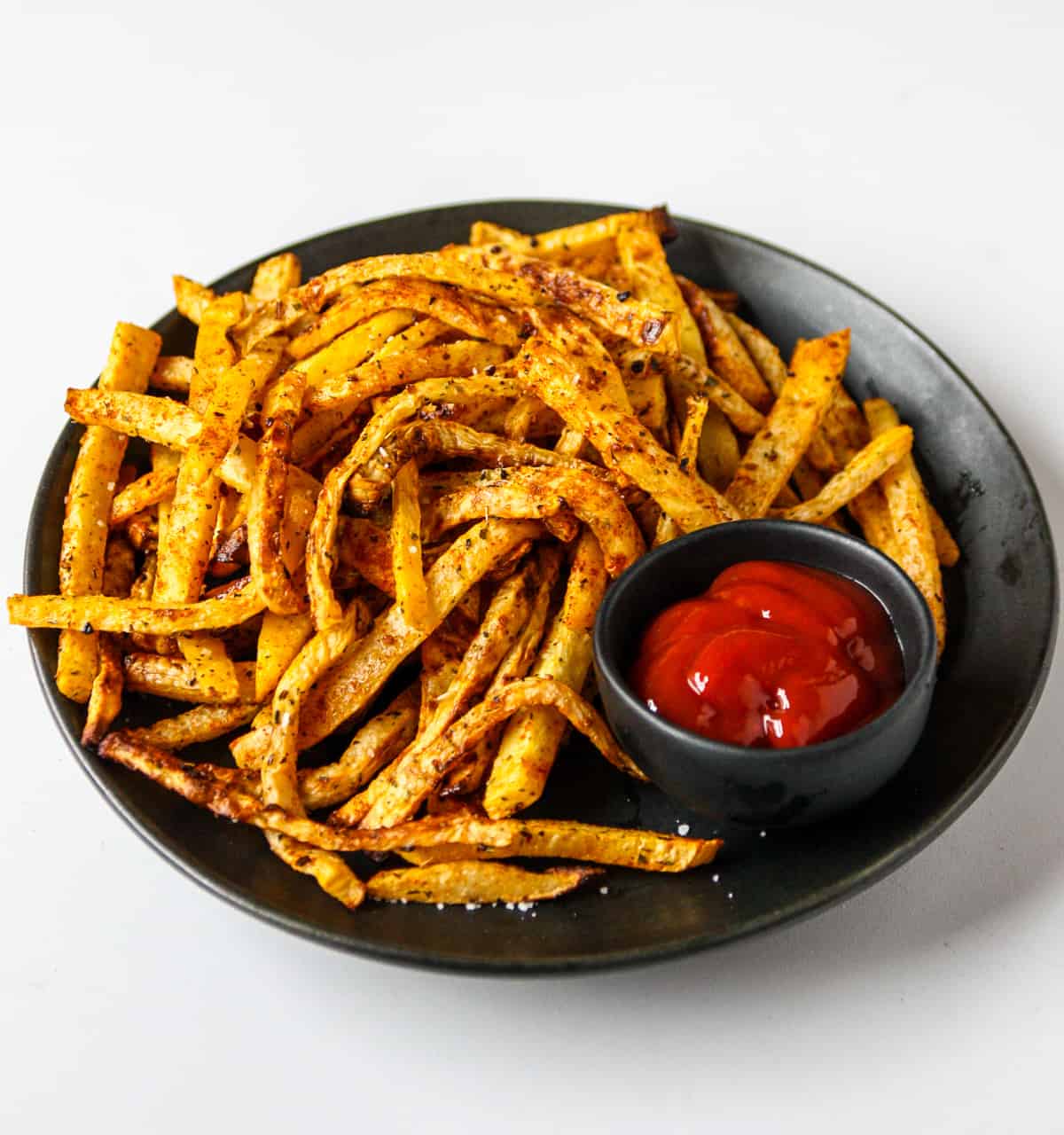 A plate full of crisp fries with ketchip.