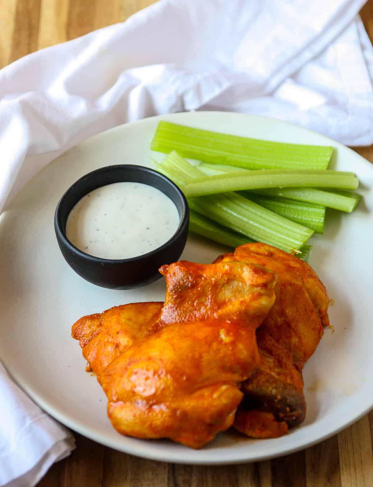 Two pieces of buffalo chicken on a plate with dipping sauce.