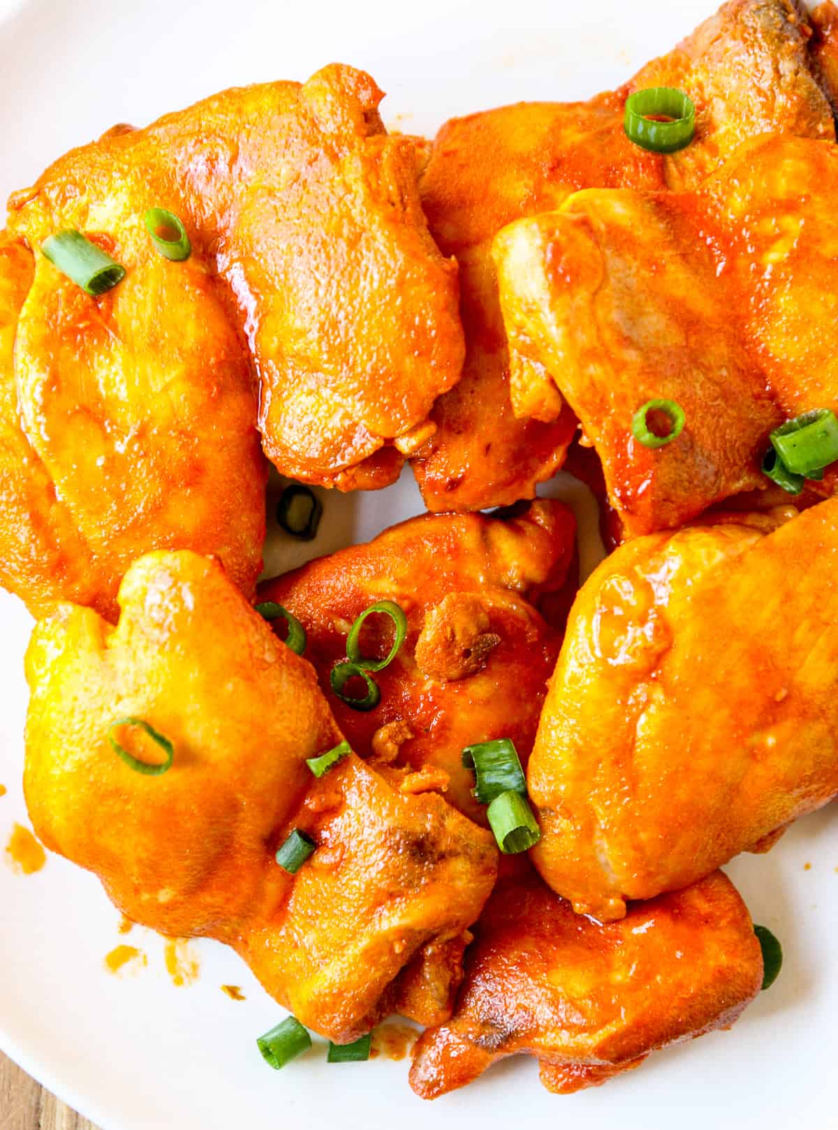 A close up of baked buffalo chicken garnished with green onion.