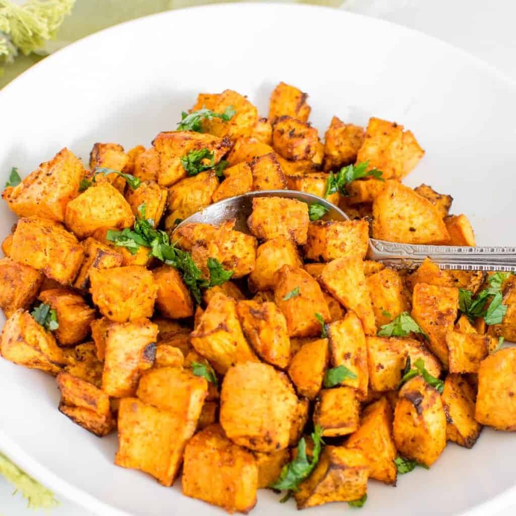 Air fried sweet potato cubes on a white plate.