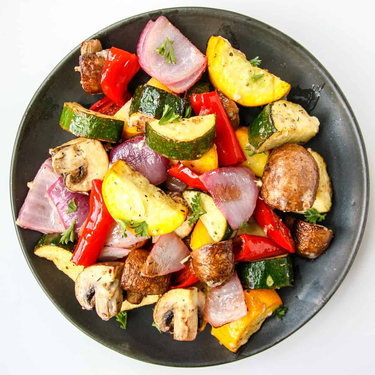 Air fryer roasted vegetables on a black plate.