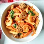 Cajun shrimp & sausage pasta in a white bowl.