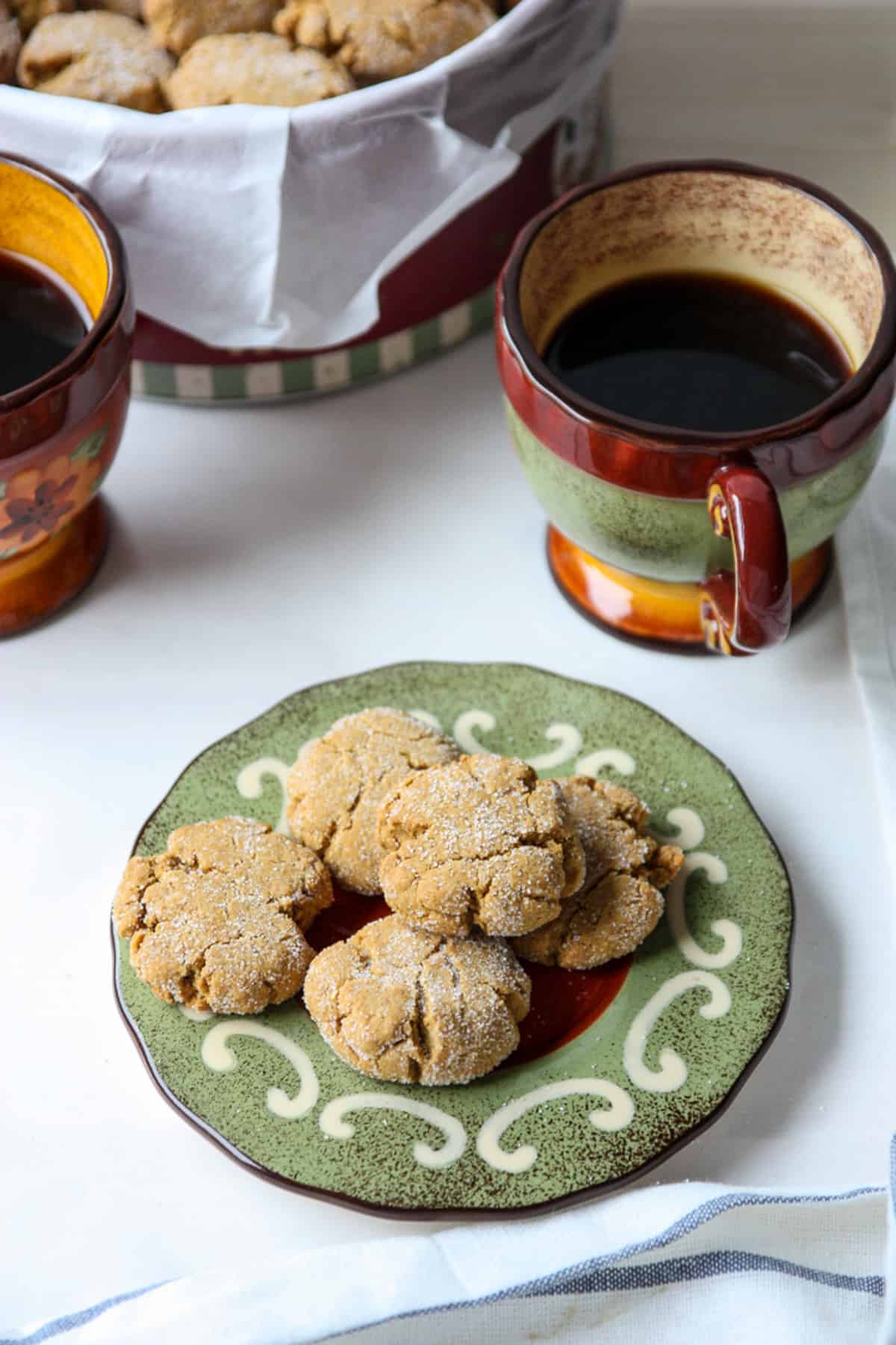 Two colorful cups of tea and a plate of cookies.