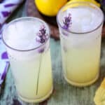 Two tall glasses of lavender lemonade with ice and garnished with sprigs of lavender.