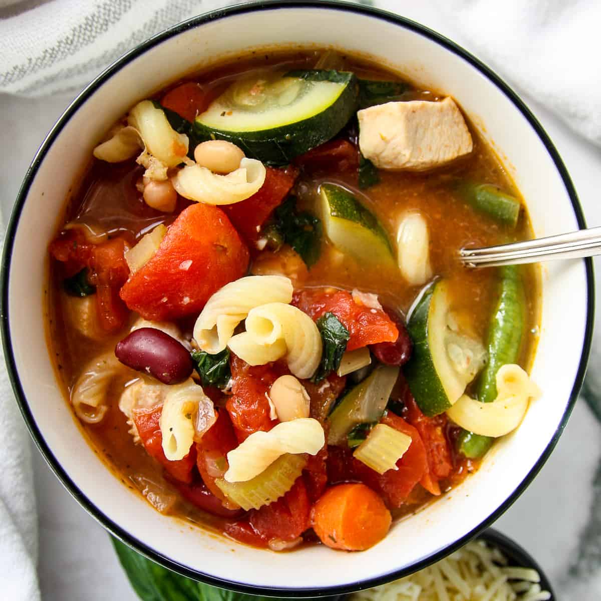 Chicken minestrone soup in a white bowl.
