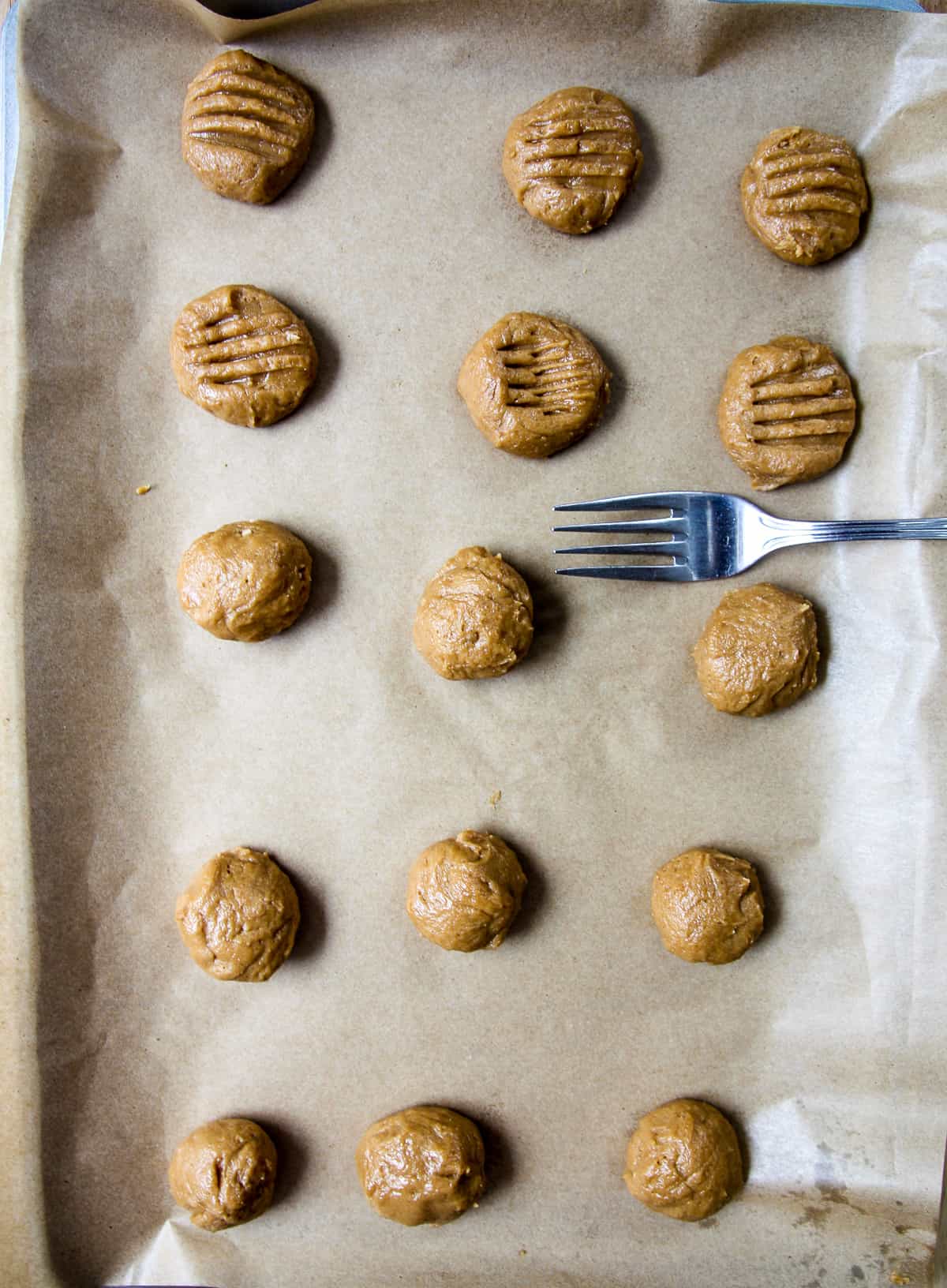 A fork being used to flatten the cookie dough balls.