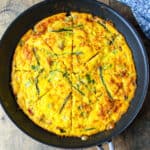 Baked ham and cheese frittata with asparagus in a skillet.