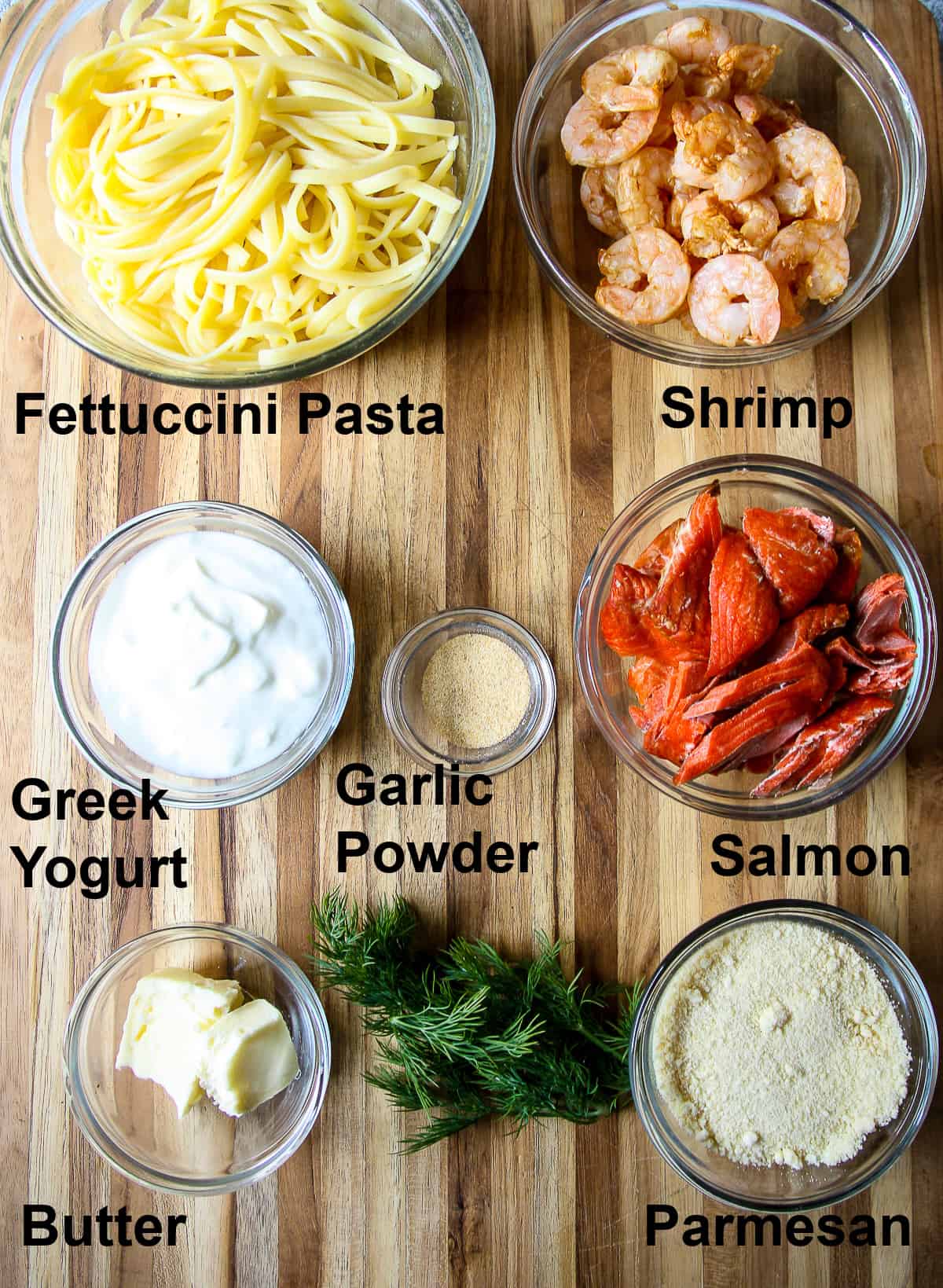 All of the ingredients needed for this recipe, in glass bowls on a wooden board.