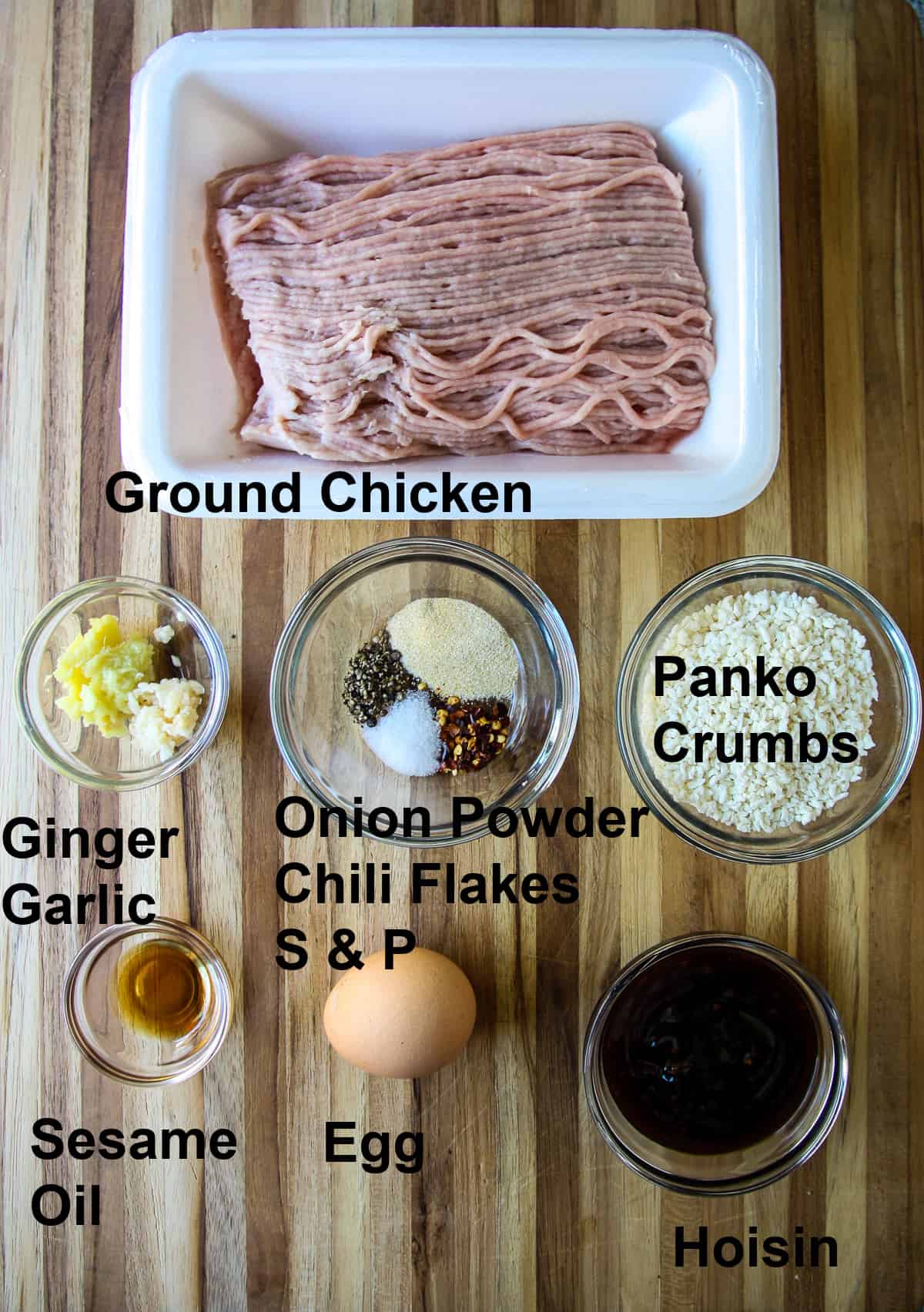 The ingredients for making the meatballs in glass bowls on a wooden board.