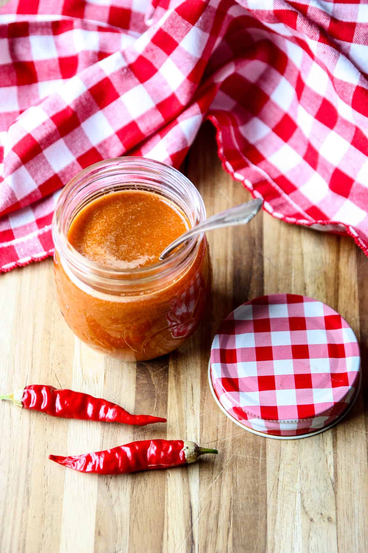 An open jar of cayenne pepper sauce with a spoon inserted.