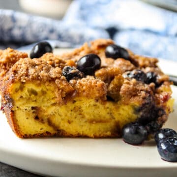 A slice of blueberry brioche French toast casserole on a white plate.